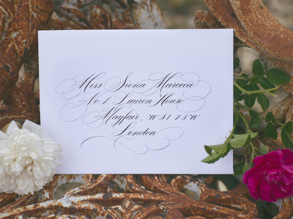 Copperplate calligraphy on invitation in beautiful Tuscan setting with flowers